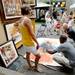 Kristen Miller, Grand Rapids, looks on as mixed media artist Hussein Saidi, of Maryland, shows Nathan MacRae, Westland, the finished painting of Michael Jordan that MacRae commissioned from Saidi during the Summer Art Fair on Wednesday. Melanie Maxwell I AnnArbor.com